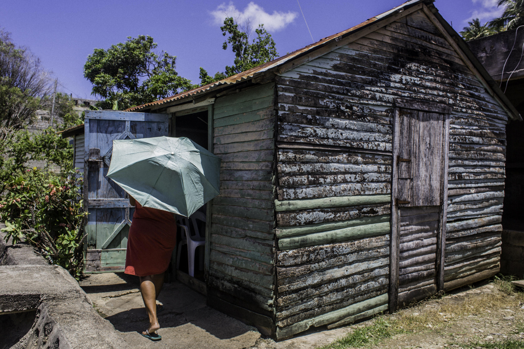 ﻿Woman walking into wooden house with blue umbrella